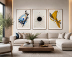 Luxury contemporary watercolor abstract wall art set featuring expressive blue, black and mustard yellow accents displayed above a large sectional sofa in a sophisticated American living room. The oversized triptych from iArt Tech Studio is professionally framed in natural oak wood with elegant white mat boards, creating a refined gallery wall that perfectly complements warm wood furniture, neutral textiles, ceramic décor, indoor plants and abundant natural daylight for a timeless modern interior.