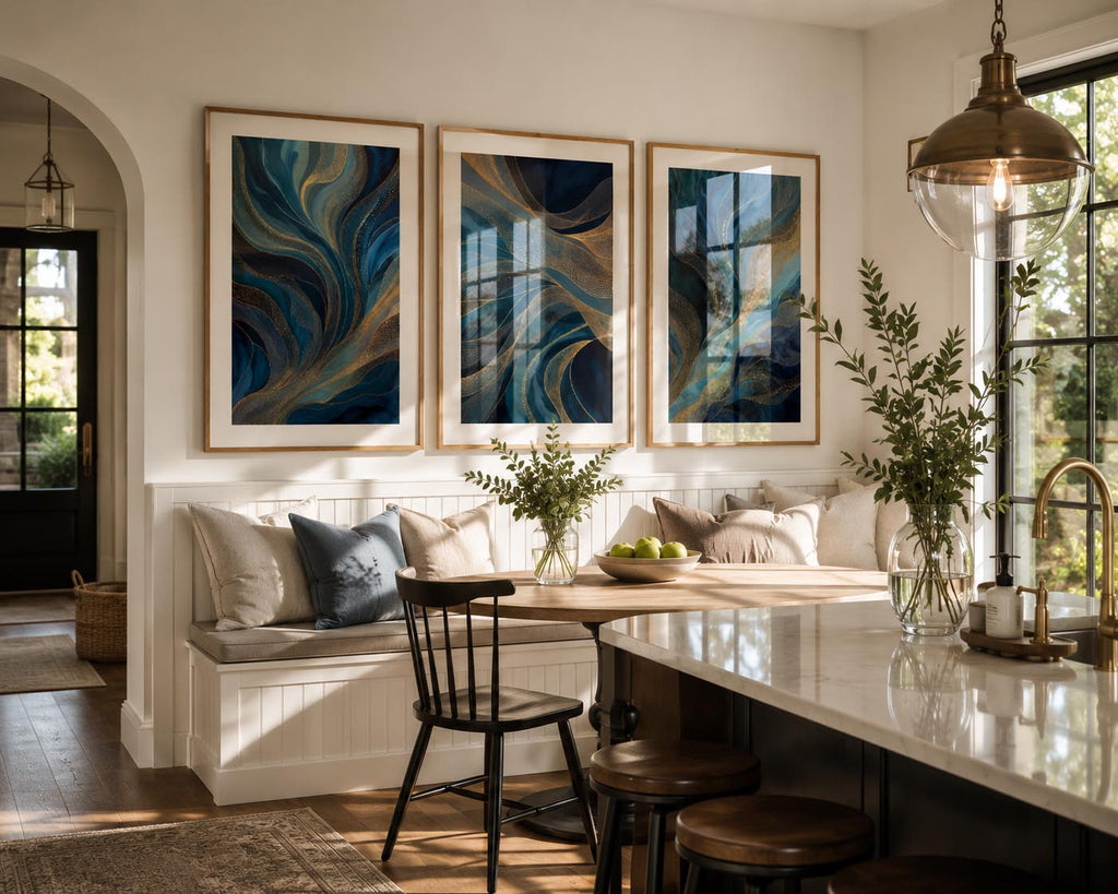 Blue Gold Modern Abstract Triptych Printable Wall Art Set of 3 showcased above a custom breakfast nook in a bright modern farmhouse kitchen with warm oak frames, white mat, marble island, pendant lighting, black windows, fresh greenery and realistic reflections on both glass and polished stone surfaces. Blue and Gold Abstract 3 Panel Gallery Wall Prints Bundle Instant Download for contemporary kitchen wall décor and open concept home styling.