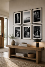 Contemporary entryway decorated with six monochrome printable photography prints from the Timeless Fine Art Gallery Wall Bundle in black frames above a natural wood console table with organic accents.